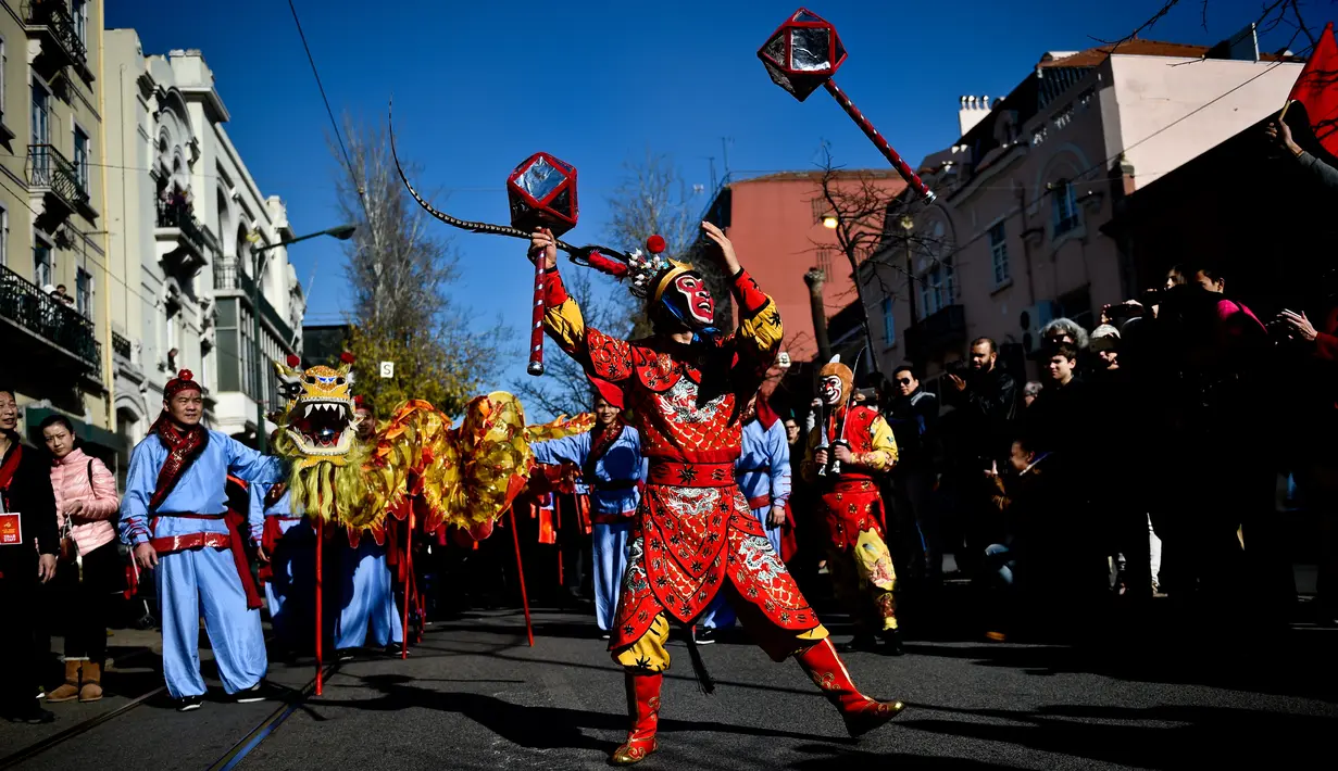 Atraksi seorang pria yang mengenakan kostum dan topeng kera saat perayaan menjelang tahun baru China di Lisbon, Portugal (21/1). Perayaan tahun baru Imlek merupakan salah satu hari besar yang dirayakan oleh kaum Tionghoa. (AFP/Patricia De Melo Moreira)