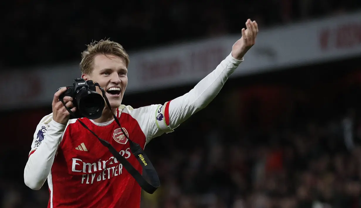 Pemain Arsenal, Martin Odegaard mengarahkan pose saat merayakan kemenangan setelah laga lanjutan Liga Inggris 2023/2024 melawan Liverpool di Emirates Stadium, London, Inggris, Minggu (05/02/2024) WIB. (AFP/Ian Kington)