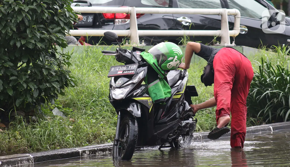 Pengendara memanfaatkan genangan air untuk mencuci kendaraan di Jalan HBR Motik Kemayoran, Jakarta, Selasa (25/2/2020). Hujan yang mengguyur Jakarta sejak Senin (24/2) malam membuat sejumlah kali meluap dan menyebabkan banjir. (Liputan6.com/Helmi Fithriansyah)
