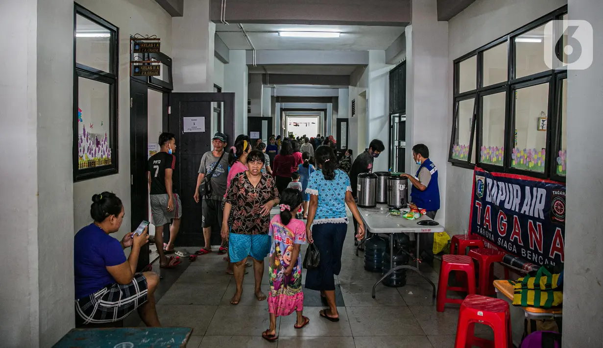 Sejumlah korban banjir berjalan di lorong gedung SDN 01/02 Kampung Melayu, Jakarta, Selasa (9/2/2021). Gedung sekolah di Kebon Pala tersebut menjadi salah satu posko pengungsian bagi sebagian korban banjir Kampung Melayu. (Liputan6.com/Faizal Fanani)