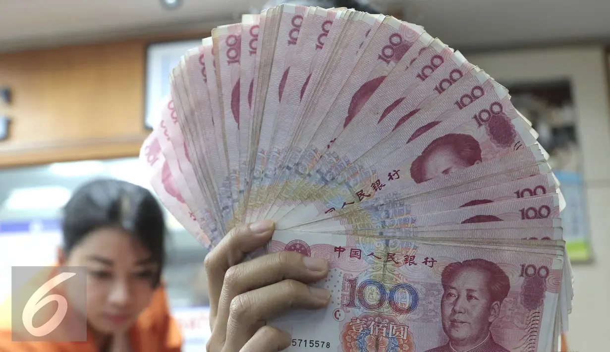 Seorang teller memperlihatkan mata uang Yuan di Jakarta, Senin (30/11). Dana Moneter Internasional (IMF), Senin (30/11), resmi memasukan yuan, atau renminbi, ke dalam special drawing rights (SDR) sebagai mata uang elite dunia. (Liputan6.com/Angga Yuniar)