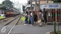 Penyeberang jalan menunggu kereta commuterline melintas di perlintasan sebidang Duren Kalibata, Jakarta, Selasa (13/9). Dirjen Kemenhub usulkan Pemprov DKI Jakarta untuk menutup 19 perlintasan sebidang di wilayah DKI Jakarta. (Liputan6.com/Yoppy Renato)
