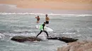 Seorang pria membawa papan selancar saat pembatasan sosial diberlakukan di Pantai Maroubra di Sydney, Australia (20/4/2020). (AFP/Saeed Khan)