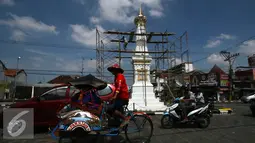 Pengendara melintas di depan Tugu,Yogakarta, Rabu (29/6). Pengerjaan renovasi dilakukan untuk memperindah monumen yang menjadi ikon kota Yogyakarta. (Liputan6.com/Boy Harjanto)