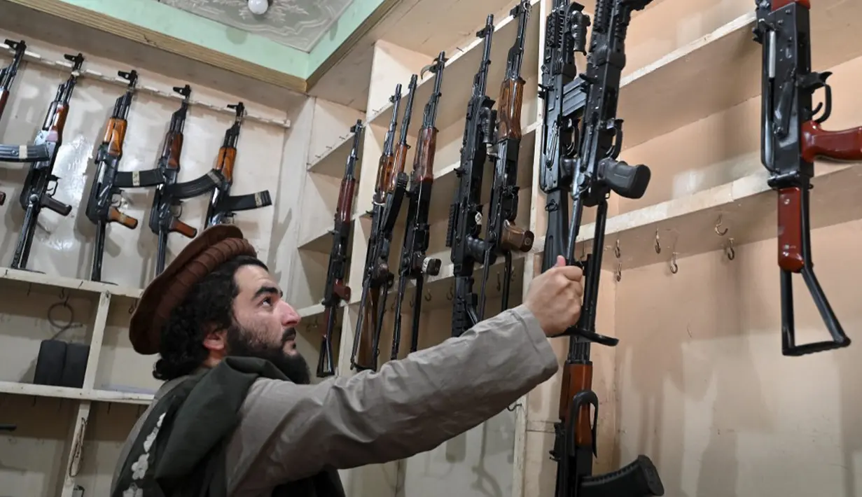 Seorang pedagang senjata Hakimullah Afridi memajang senapan otomatis buatan lokal di tokonya, Darra Adamkhel, Pakistan, 14 Desember 2022. Pasar gelap senjata di Kota Darra Adamkhel dipenuhi dengan senapan Amerika palsu, replika revolver, dan AK-47 palsu. (Abdul MAJEED/AFP)