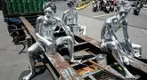 Foto yang diambil pada 7 April 2025 ini menunjukkan manusia silver Keris Munandar (kanan), saudaranya Ari Munandar (kiri), dan tetangganya Riyan Ahmad Fazriyansah menumpang di bagian belakang truk kontainer untuk mencapai persimpangan di Jakarta. (Yasuyoshi CHIBA/AFP)