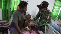 Tim medis dari satuan tugas militer Indonesia memeriksa seorang anak yang sedang menyusu pada ibunya di rumah sakit setempat di Agats, Asmat, provinsi Papua Barat (26/1). (AFP/Bay Ismoyo)