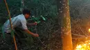 Petugas menggunakan ranting pohon untuk memadamkan api. (merdeka.com/Arie Basuki)