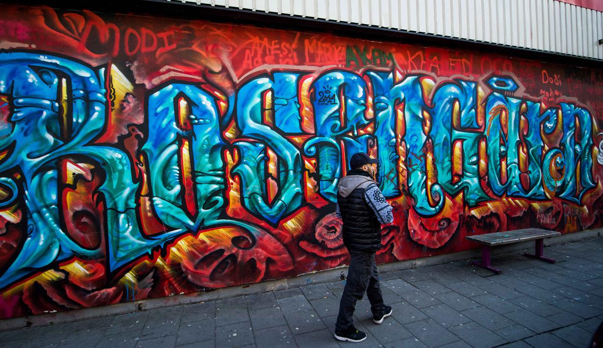 Seorang pwarga berjalan melewati tembok graffiti  dekat lapangan sepak bola Zlatan di kawasan Rosengard, Malmoe, (2/5/2016). (AFP/Jonathan Nackstrand)
