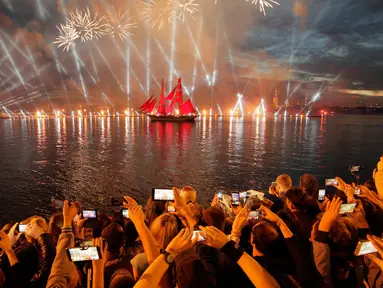 Orang-orang menonton kembang api dan perahu berlayar merah saat White Nights Festival di St.Petersburg, Rusia (24/6). Atraksi terbesar untuk memperingati White Nights adalah Alye Parusa atau Scarlet Sails (Layar Merah). (AP/Dmitri Lovetsky)