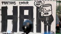 Mural bertuliskan "Mana HAM" terpampang saat aksi Kamisan ke-502 di seberang Istana Merdeka, Jakarta, Kamis (10/8). Aksi meminta pemerintah mewujudkan komitmen dalam menyelesaikan kasus pelanggaran HAM berat pada masa lalu. (Liputan6.com/Johan Tallo)