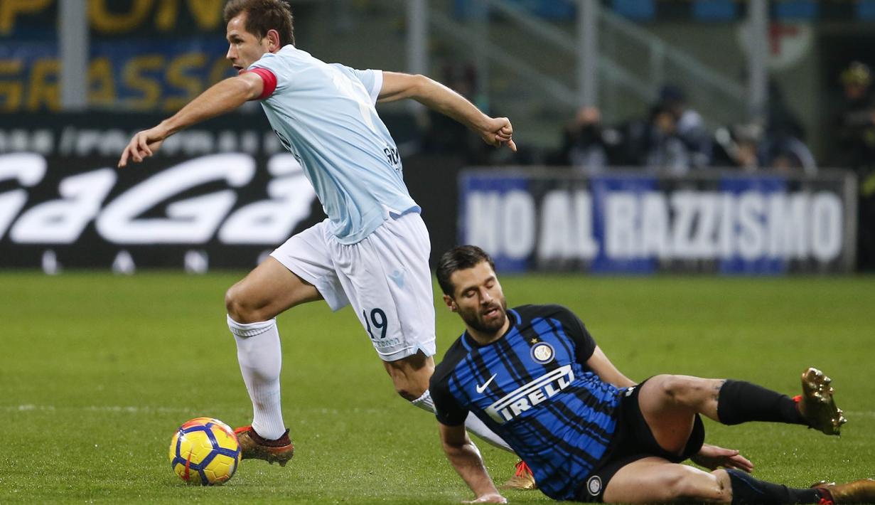 Gelandang Inter Milan, Antonio Candreva, terjatuh saat berebut bola dengan kapten Lazio, Senad Lulic, pada laga Serie A, Italia, di Stadion Giuseppe Meazza, Milan Sabtu (30/12/2017). Inter Milan ditahan imbang 0-0 oleh Lazio. (AP/Antonio Calanni)