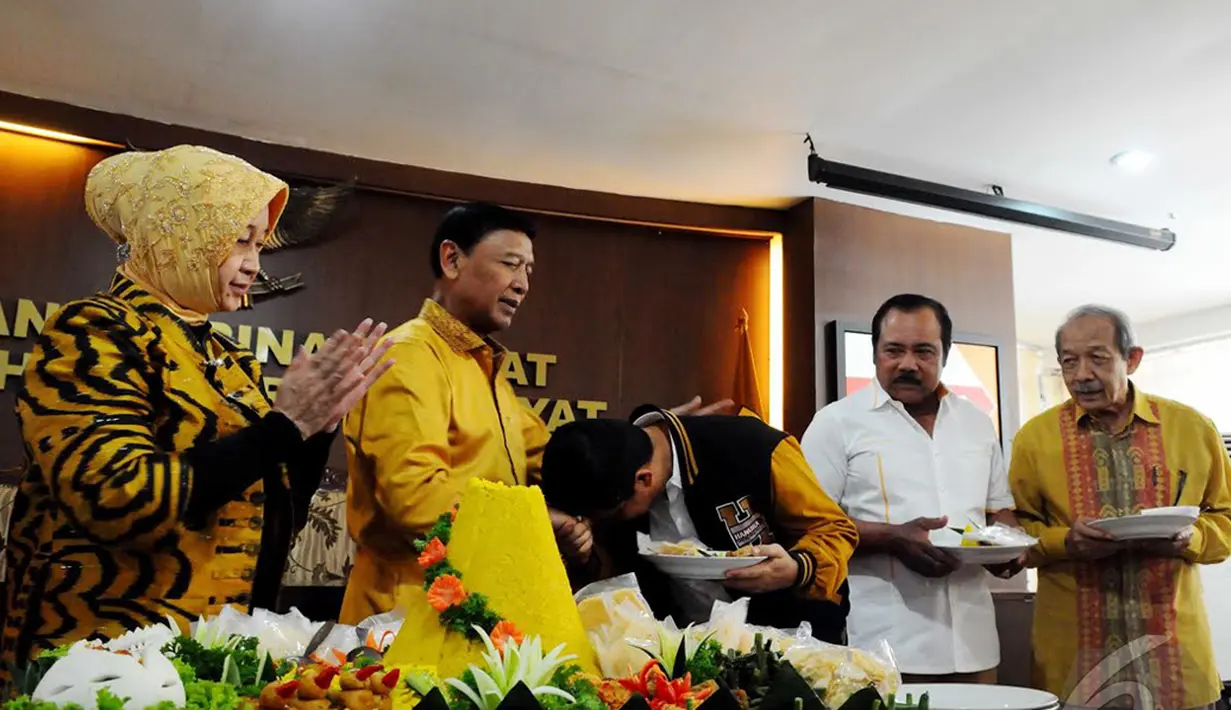 Ketua Umum Hanura Wiranto menyerahkan potongan tumpeng kepada Yuddy Chrisnandi saat peringatan HUT ke-8 Partai Hanura di Kantor DPP Partai Hanura, Jakarta,Minggu (21/12/2014) (Liputan6.com/Andrian Martinus)