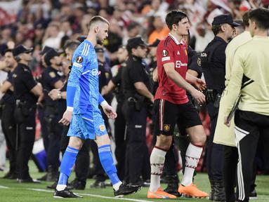 Pemain Manchester United, David De Gea dan Harry Maguire meninggalkan lapangan setelah ditaklukkan Sevilla pada leg kedua perempat final di Ramon Sanchez Pizjuan, Jumat (21/4/2023). Kedua pemain ini menjadi sorotan lantaran menjadi biang kerok kekalahan Setan Merah. (AFP/Cristina Quicler)