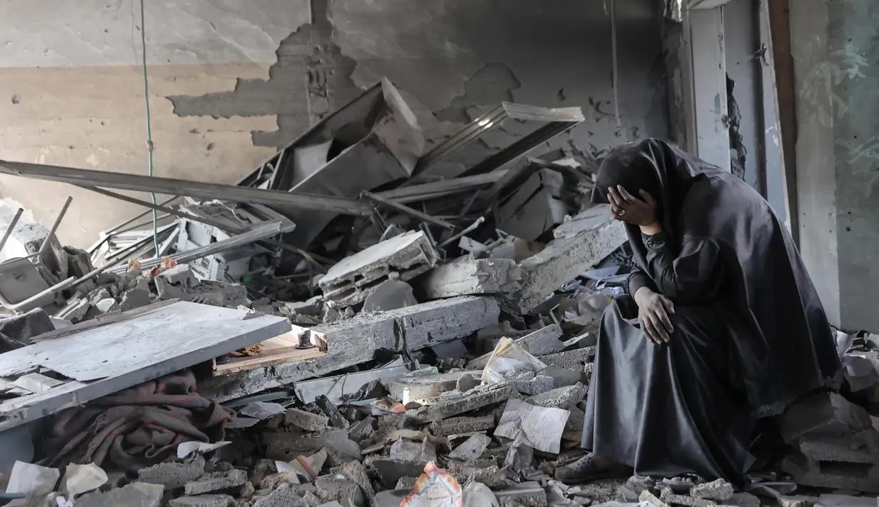 Ekspresi seorang wanita Palestina ketika duduk di tengah puing-puing Sekolah Yaffa di lingkungan Tuffah, Kota Gaza, setelah serangan Israel semalaman, pada Senin 30 Juni 2025. (Omar AL-QATTAA/AFP)