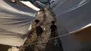 Anak-anak Palestina yang mengungsi akibat pemboman Israel di Jalur Gaza berjalan di tenda kamp yang disediakan UNDP di Khan Younis, Kamis (19/10/2023). (AP Photo/Fatima Shbair)