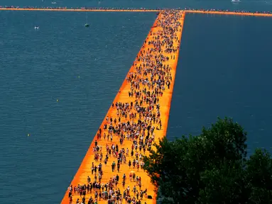 Ribuan orang berjalan di atas sebuah instalasi "The Floating Piers" yang merupakan karya seniman Bulgaria, Christo Vladimirov Javacheff di Danau Iseo, Italia, (24/6). Karya menakjubkan ini diharapkan dapat menarik wisatawan. (REUTERS/Stefano Rellandini)