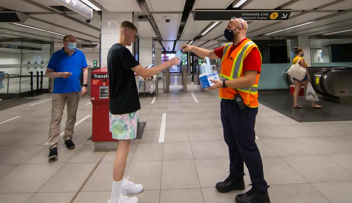 Seorang staf Toronto Transit Commission (TTC) membagikan masker baru kepada penumpang di stasiun kereta bawah tanah di Toronto, Kanada, pada 2 Juli 2020. TTC mewajibkan para pengguna layanan kereta memakai masker atau penutup wajah mulai Kamis (2/7) karena pandemi COVID-19. (Xinhua/Zou Zheng)