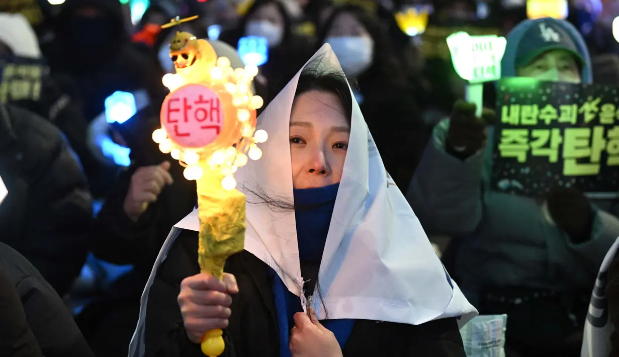 Salah satu pengunjuk rasa melambaikan tongkat cahaya (light stick) saat mereka mengambil bagian dalam protes yang menyerukan penggulingan Presiden Korea Selatan Yoon Suk Yeol di sebuah jalan dekat Majelis Nasional di Seoul pada tanggal 13 Desember 2024. (Jung Yeon-je/AFP)