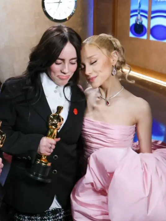 Billie mengenakan busana dari Chanel saat hadir di red karpet Oscar. Ia tampil mengenakan atasan kemeja berkancing putih bersih di bawah blazer hitam. [@arianagrande]