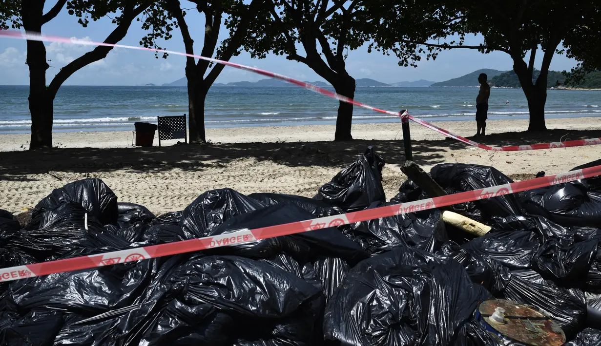 Tumpukan kantong plastik berisi sampah di tepi sebuah pantai di Hong Kong, Senin (7/8). Kecelakaan kapal pengangkut minyak sawit di perairan sekitar Hong Kong memaksa negara di bawah kedaulatan China itu menutup 10 pantainya. (Anthony WALLACE / AFP)