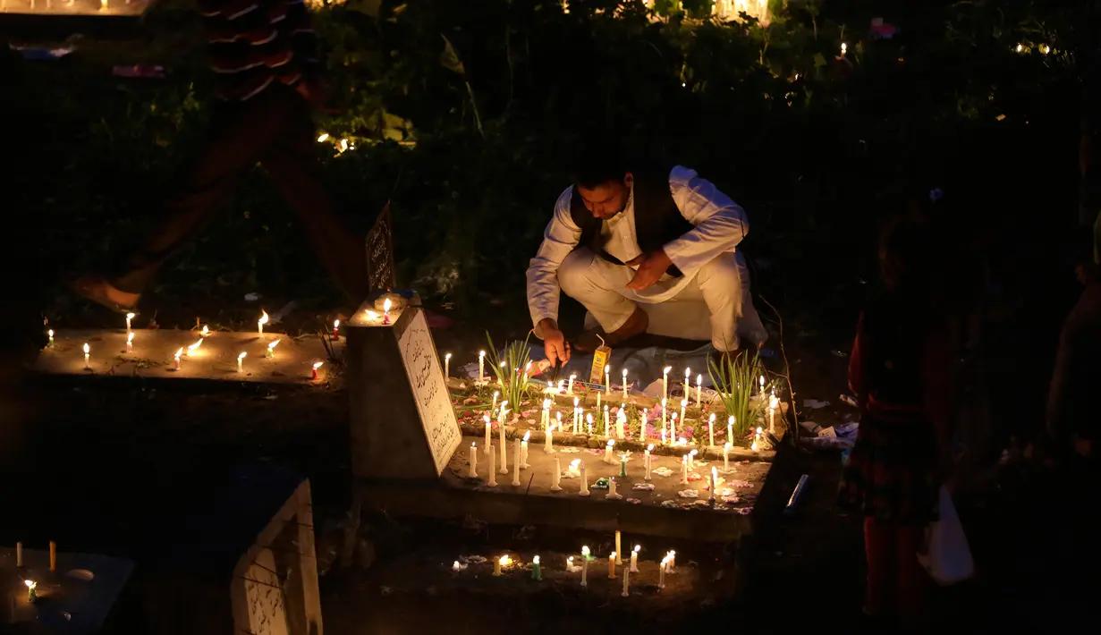 Seorang pria menyalakan lilin di pemakaman keluarga dan saudara mereka saat memperingati Shab-e-Barat di pinggiran Srinagar, Kashmir (11/5). (AP Photo / Mukhtar Khan)