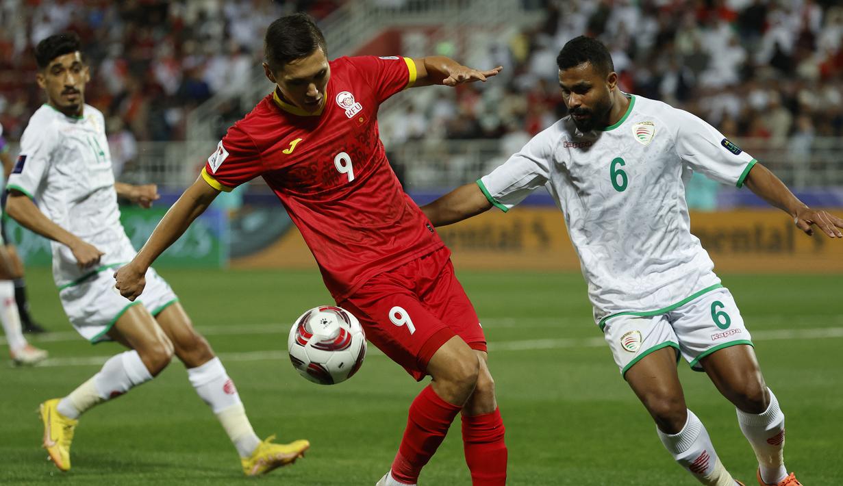 Striker Timnas Kirgistan, Ernist Batyrkanov (kiri) menguasai bola dibayangi bek Oman, Ahmed al-Khamisi pada laga ketiga Grup F Piala Asia 2023 di Abdullah bin Khalifa Stadium, Doha, Qatar, Kamis (25/1/2024). (AFP/Karim Jaafar)