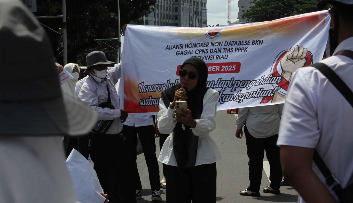 Aksi ini merupakan bentuk protes terhadap diskriminasi dalam seleksi CASN/PPPK 2024, ketiadaan aturan yang menjamin keberlanjutan status kerja, serta ancaman Pemutusan Hubungan Kerja (PHK) dan peralihan ke sistem outsourcing yang semakin meluas. Tampak dalam foto, massa dari Aliansi Honorer Non Database BKN Gagal Calon Pegawai Negeri Sipil (CPNS) Indonesia saat menggelar Aksi Damai Jilid 2 Nasional di kawasan Silang Selatan Monumen Nasional, Jakarta Pusat, pada Senin (17/11/2025). (merdeka.com/magang/Rendi Saputra)