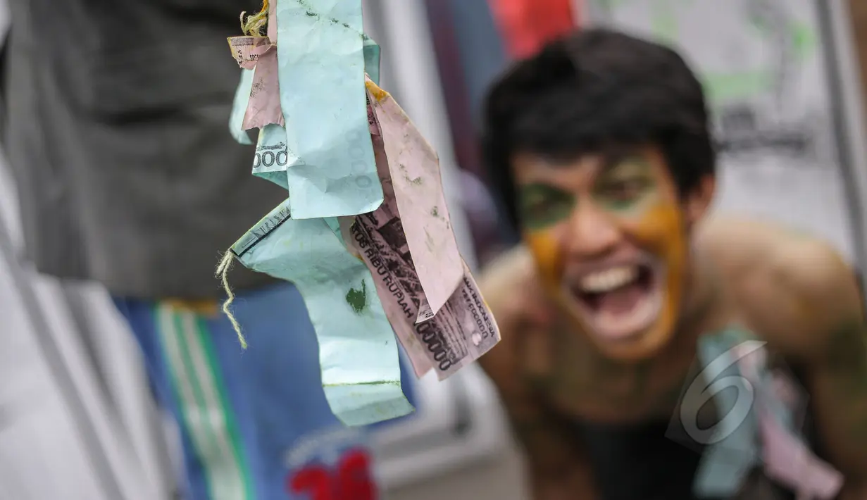 Mahasiswa melakukan aksi teatrikal yang menggambarkan pendidikan di Indonesia yang masih terbelenggu oleh uang, dalam rangka memperingati Hari Pendidikan Nasional (Hardiknas) di Bundaran HI, Jakarta, Minggu (3/5/2015). (Liputan6.com/Faizal Fanani)