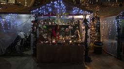 Seorang perempuan Palestina memamerkan hadiah artistik buatan tangan di sebuah kios di pasar kerajinan tradisional Natal, di kota Ramallah, Tepi Barat, Rabu, 7 Desember 2022. Warga Palestina memulai musim belanja tradisional Natal sebagai persiapan untuk liburan yang akan datang. (AP Photo/Nasser Nasser)