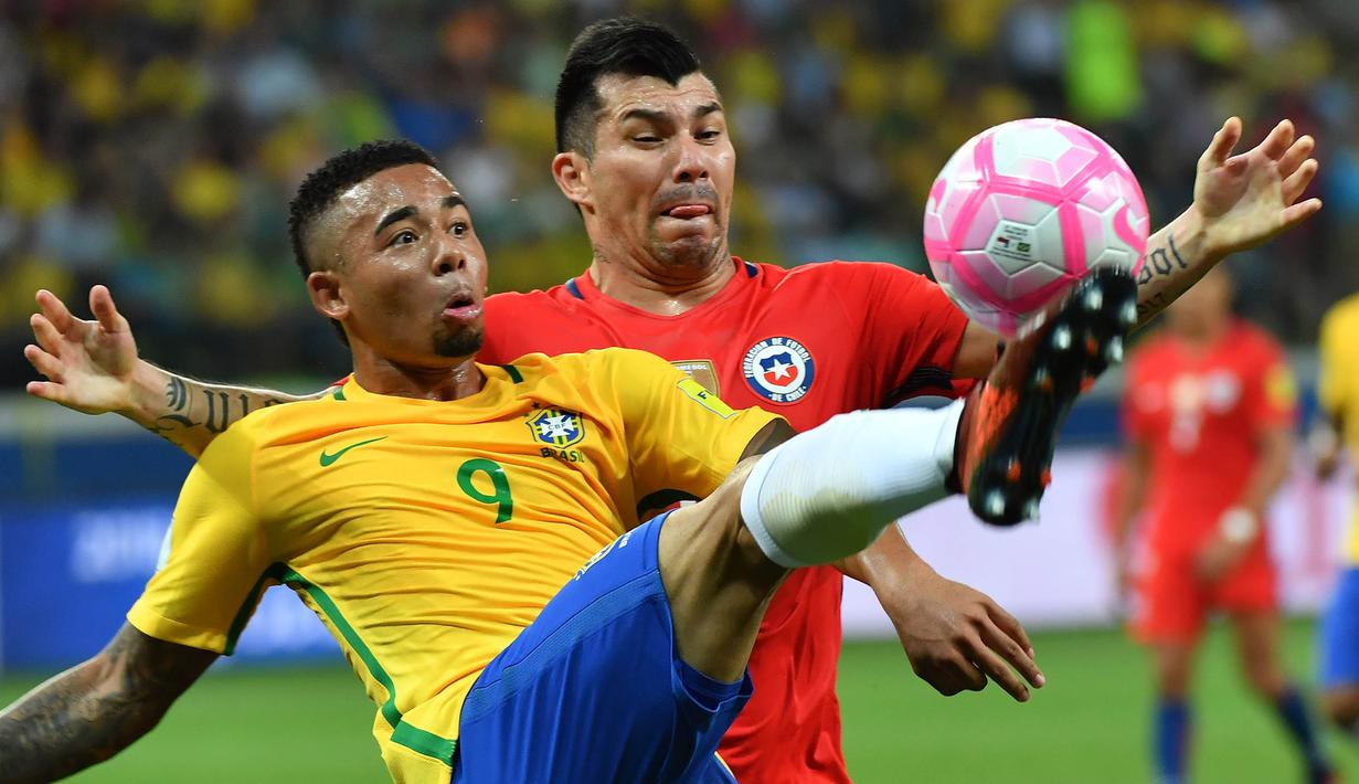 Striker Brasil, Gabriel Jesus, berebut bola dengan gelandang Cile, Gary Medel, pada laga kualifikasi Piala Dunia 2018 di Stadion Allianz Parque, Sao Paulo, Selasa (10/10/2017). Brasil menang 3-0 atas Cile. (AFP/Nelson Almeida)