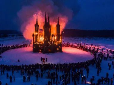 Sejumlah warga menonton bangunan bergaya gothik karya seniman Nikolay Polissky yang dibakar saat perayaan Shrovetide di wilayah Kaluga, Rusia (17/2). Perayaan ini menandai berakhirnya musim dingin yang dirayakan sejak masa pagan. (AFP/Dmitry Serebryakov)
