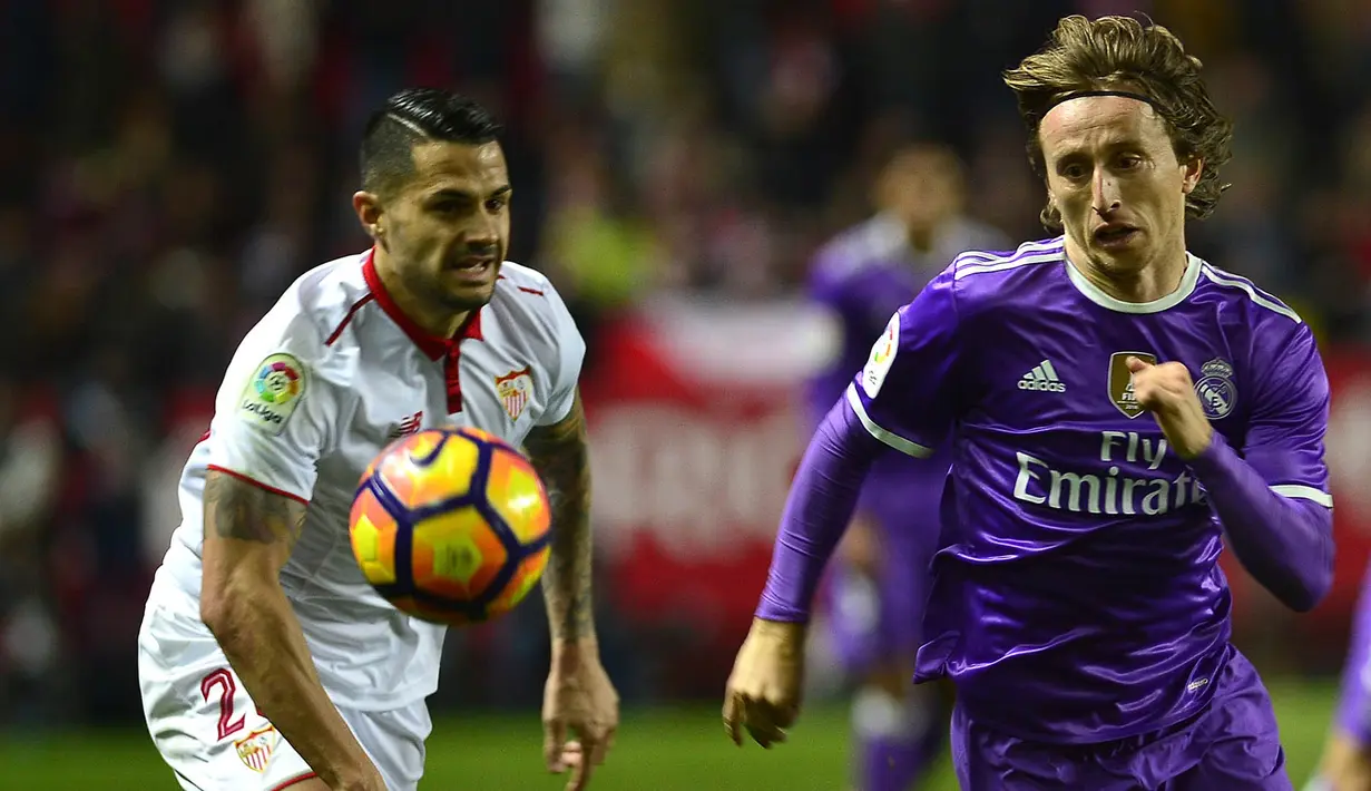 Gelandang Real Madrid, Luka Modric, berebut bola dengan gelandang Sevilla, Vitolo. Selaku tuan rumah, Sevilla sedikit lebih menguasai jalannya laga menurut angka persentase penguasaan bola 54 persen. (AFP/Cristina Quicler)