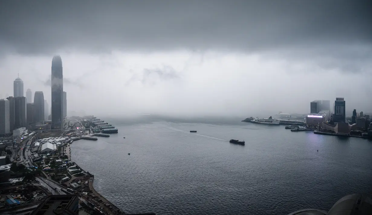 Pemandangan gedung IFC (International Finance Center) menjulang di atas dermaga Central saat badai awan terjadi sebelum hujan lebat di atas Pelabuhan Victoria Hong Kong (6/3). (AFP Photo/Anthony Wallace)
