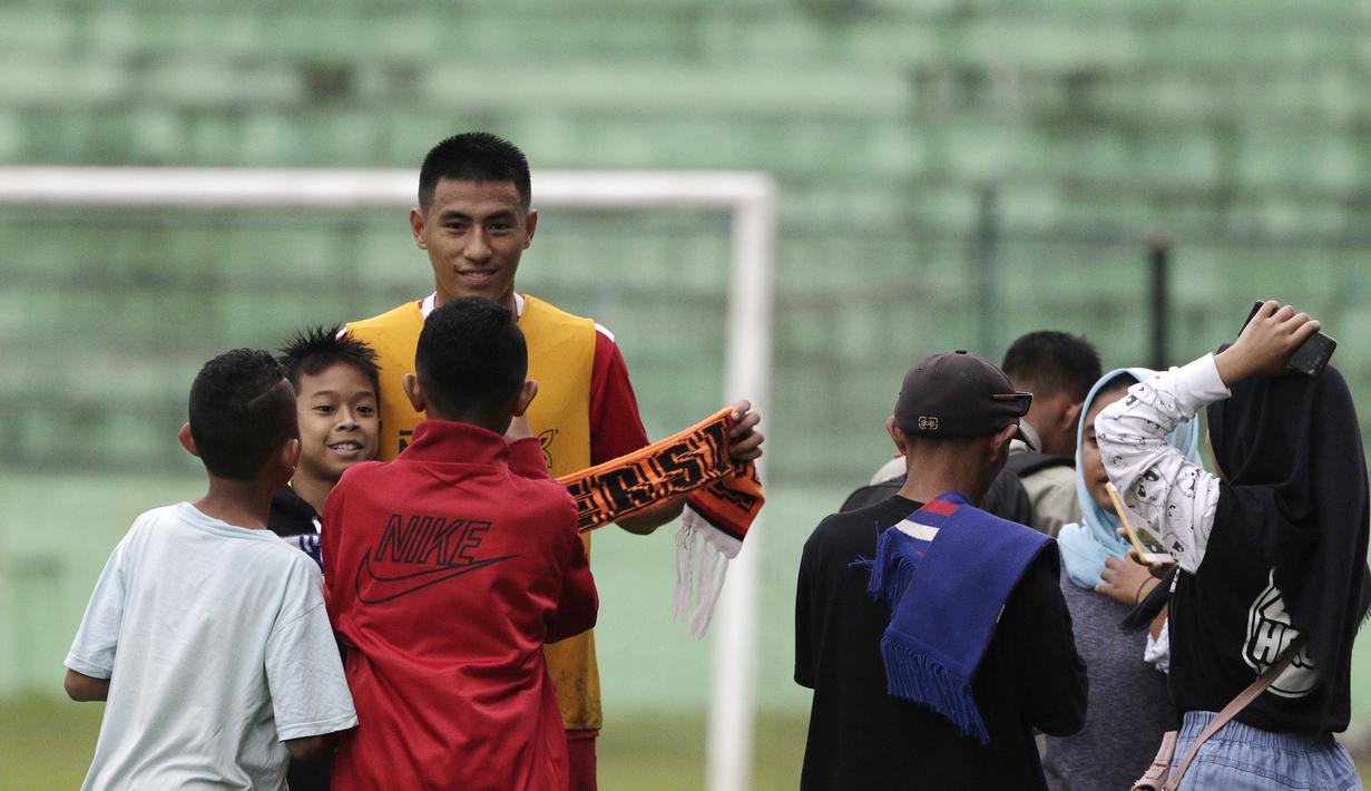 Pemain Arema FC, Hanif Sjahbandi, foto bersama dengan fans usai sesi latihan di Stadion Gajayana, Malang, Kamis (11/4). Setelah sesi latihan, pemain Arema FC melayani permintaan fans untuk foto bersama. (Bola.com/Yoppy Renato)