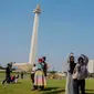 Beberapa remaja berswafoto berlatar Monumen Nasional (Monas), Jakarta, Kamis (8/2/2024). (Liputan6.com/Angga Yuniar)