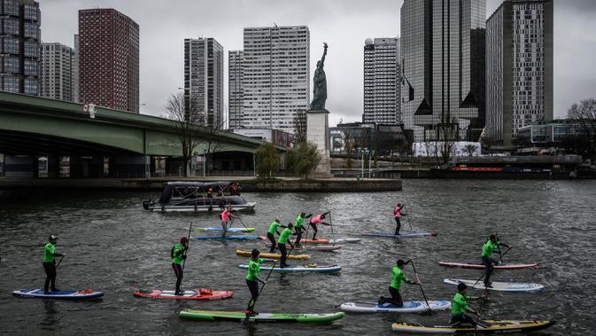 Peserta mengikuti lomba dayung sambil berdiri pada edisi ke-10 Nautic Paddle Race di Sungai Seine, Paris, Minggu (8/12/2019). Sekitar 1000 pesaing ikut serta dalam lomba sejauh 11 kilometer menyeberangi sungai Seine dengan pemandangan kota Paris. (Photo by Olivier MORIN / AFP)