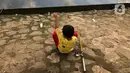 Seorang anak memancing ikan di kubangan yang berada di Jalan DI Panjaitan, Jatinegara, Jakarta, Selasa (16/6/2020). Meski telah dipagari, sejumlah warga tetap memancing ikan di lokasi yang merupakan saluran pembuangan tersebut. (Liputan6.com/Immanuel Antonius)
