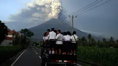 Para pelajar berdiri di sebuah mobil untuk pergi ke sekolah di tengah erupsi Gunung Agung di Karangasem, Bali, Selasa, (28/11). Erupsi Gunung Agung yang masih terjadi menyebabkan Bandara Ngurah Rai ditutup. (AP Photo/Firdia Lisnawati)
