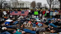 Belasan siswa SMA bersama dengan pengunjuk rasa berbaring di jalan depan Gedung Putih, Washington, Senin (19/2). Mereka memprotes mengenai peraturan pengendalian senjata di Amerika Serikat. (AP Photo/Evan Vucci)