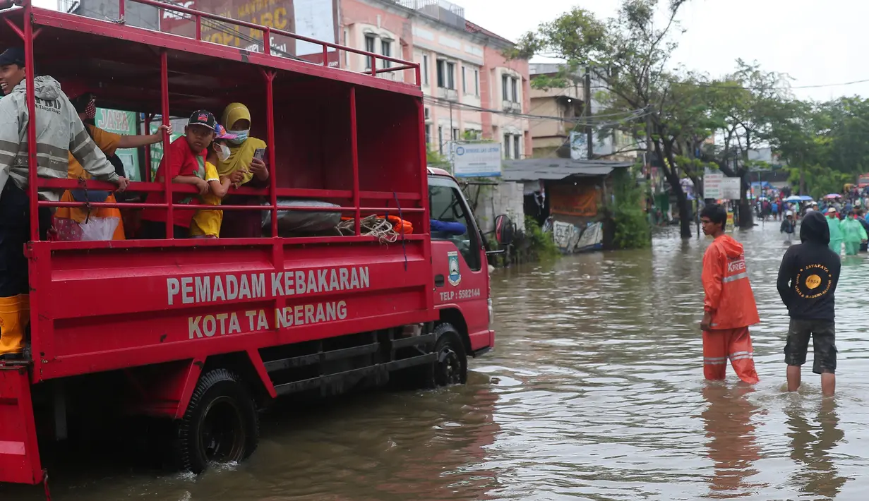 Warga menaiki mobil milik pemadam kebakaran Kota Tangerang untuk melintasi genangan air ketika banjir merendam Jalan KH. Hasyim Ashari, Tangerang, Banten, Sabtu (16/7/2022). Akibat luapan kali angke ruas jalan yang menghubungkan Tangerang-Jakarta itu terputus akibat banjir. (Liputan6.com/Angga Yuniar)