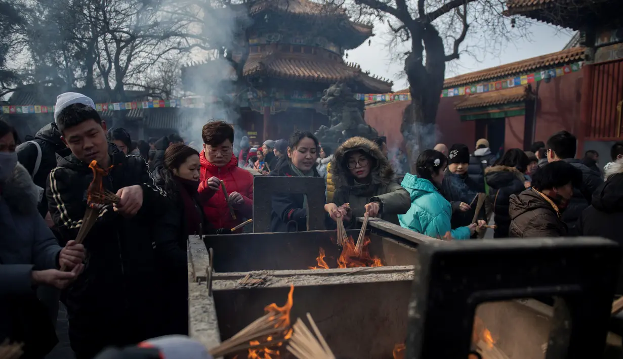 Sejumlah warga membakar dupa untuk berdoa keberuntungan pada hari kelima Tahun Baru Imlek di Yonghegong, atau Kuil Lama di Beijing (9/2). Warga China merayakan Tahun Babi tersebut dengan doa, pesta keluarga, dan belanja. (AFP Photo/Nicolas Asfouri)