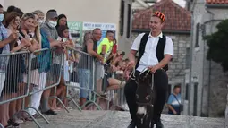 Seorang pria menunggangi keledai dalam kompetisi balap keledai tradisional ke-53 di Tribunj, Kroasia (29/8/2020). (Xinhua/Pixsell/Hrvoje Jelavic)
