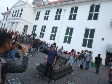 Pengunjung berfoto di depan meriam di kawasan wisata Kota Tua, Jakarta, Senin (12/12). Kota Tua masih menjadi salah satu destinasi wisata bagi warga Jakarta dan sekitarnya untuk menghabiskan waktu liburan. (Liputan6.com/Immanuel Antonius)