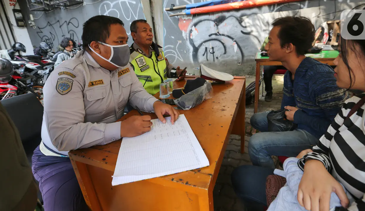 Petugas memberi peringatan kepada pengendara bermotor karena tidak menggunakan masker dan helm pada pada hari pertama PSBB di jalur check point Jalan Ir. H Juanda, Ciputat, Tangerang Selatan, Sabtu (18/4/2020). Selama PSBB pengendara wajib kenakan masker. (Liputan6.com/Fery Pradolo)