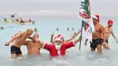 Seorang pria berkostum Sinterklas berendam di laut saat ambil bagian dalam mandi natal di kota Nice, Prancis Selatan, Minggu (16/12). Kegiatan ini merupakan bagian dari perayaan tradisional Natal bagi warga Prancis. (Photo by YANN COATSALIOU / AFP)