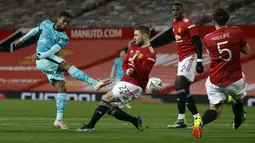 Gelandang Liverpool, Georginio (kiri) Wijnaldum menendang bola yang dihalangi oleh bek Manchester United, Luke Shaw dalam laga putaran keempat Piala FA di Stadion Old Trafford, Senin dinihari WIB (25/1/2021). Manchester United atau MU singkirkan Liverpool usai menang 3-2. (Phil Noble/Pool via AP)