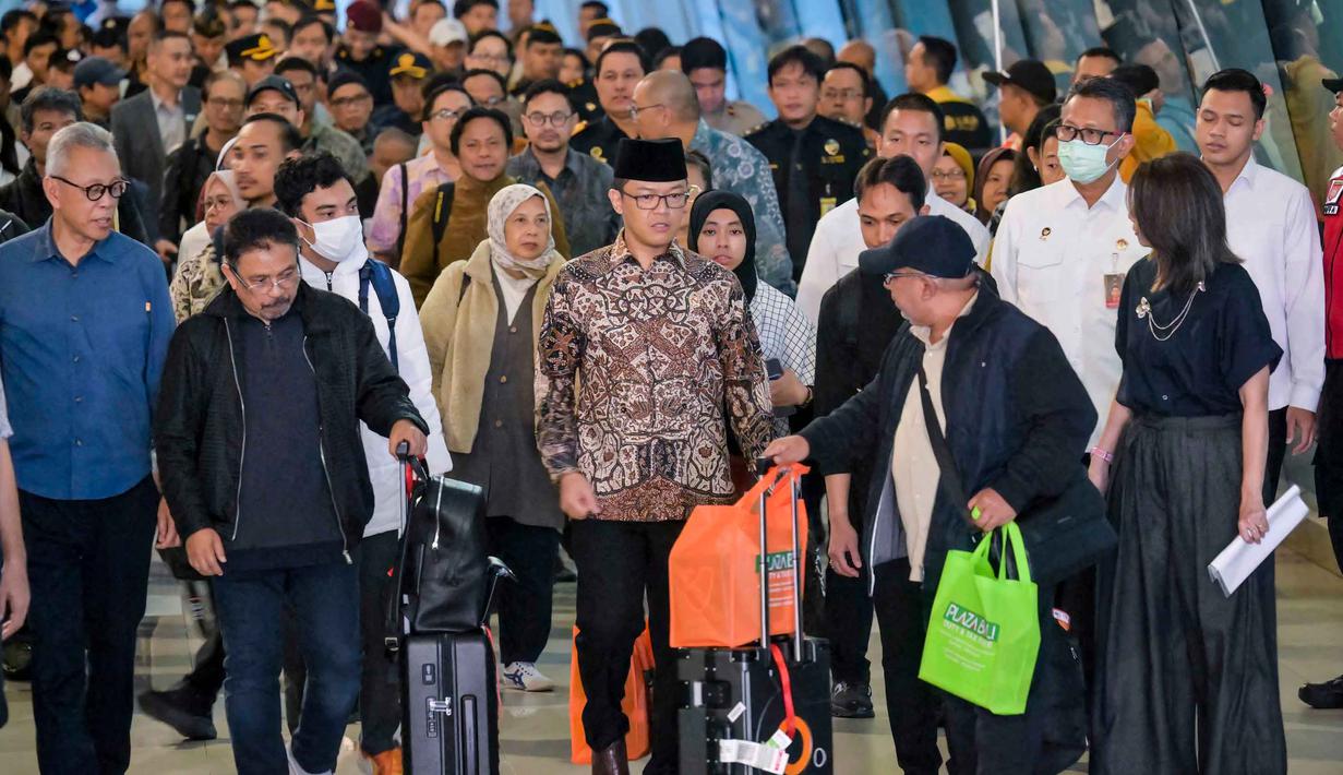 Menteri Luar Negeri Indonesia, Sugiono (tengah), berjalan bersama Warga Negara Indonesia yang kembali dari Iran tiba di Bandara Internasional Soekarno-Hatta, Tangerang, Banten, pada Selasa 10 Maret 2026. 22 Warga Negara Indonesia (WNI) yang dievakuasi dari Iran tiba di Indonesia melalui Bandara Internasional Soekarno-Hatta, Tangerang, Banten pada Selasa 10 Maret 2026. (BAY ISMOYO/AFP)