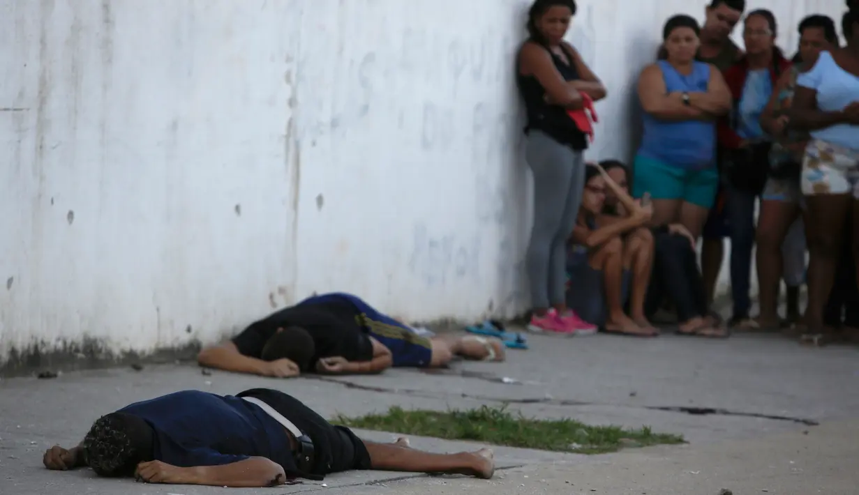 Warga melihat jenazah yang diduga pengedar narkoba di Pavuna, Rio de Janeiro, Brasil, Kamis (30/3). Dua pengedar dan seorang mahasiswi tewas tertembak saat proses penangkapan pengedar tersebut. (AP Photo / Diego Herculano)