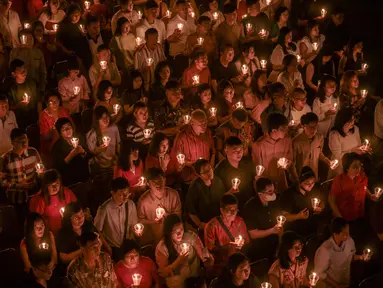 Umat Kristiani menyalakan lilin selama misa Hari Natal di Gereja Bethany, Surabaya, Jawa Timur pada Kamis 25 Desember 2025. Puluhan ribu umat Kristiani memadati Gereja Bethany Nginden Surabaya untuk mengikuti ibadah Natal pada Kamis (25/12/2025) malam. (JUNI KRISWANTO/AFP)